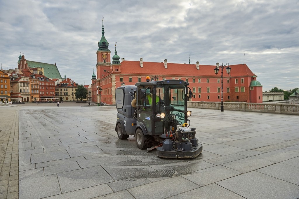 Szorowarka czyści chodnik, w tle Plac Zamkowy i Zamek Królewski w Warszawie