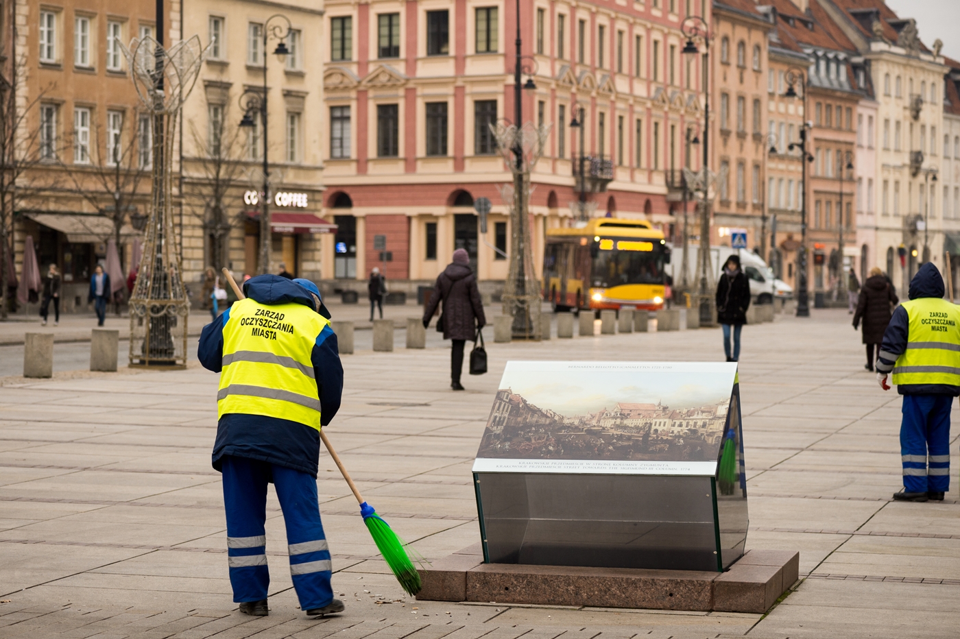 Pracownik ekipy porządkowej zamiata chodnik na Krakowskim Przedmieściu