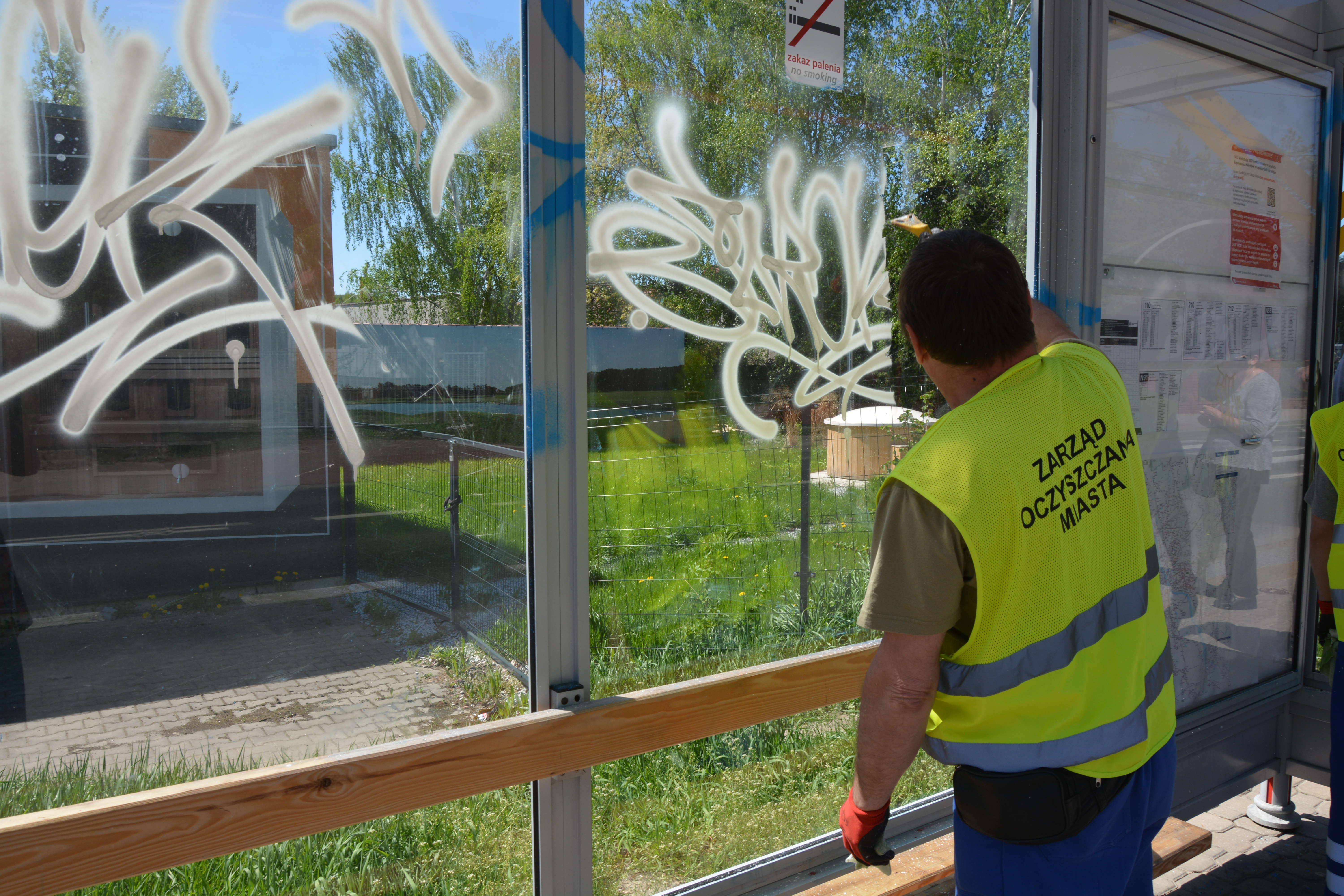 Pracownik Zarządu Oczyszczania Miasta czyści wiatę z pseudograffiti