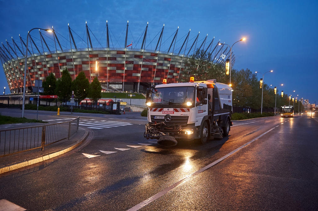 Zamiatarka czyści jezdnię nocą, w tle Stadion Narodowy