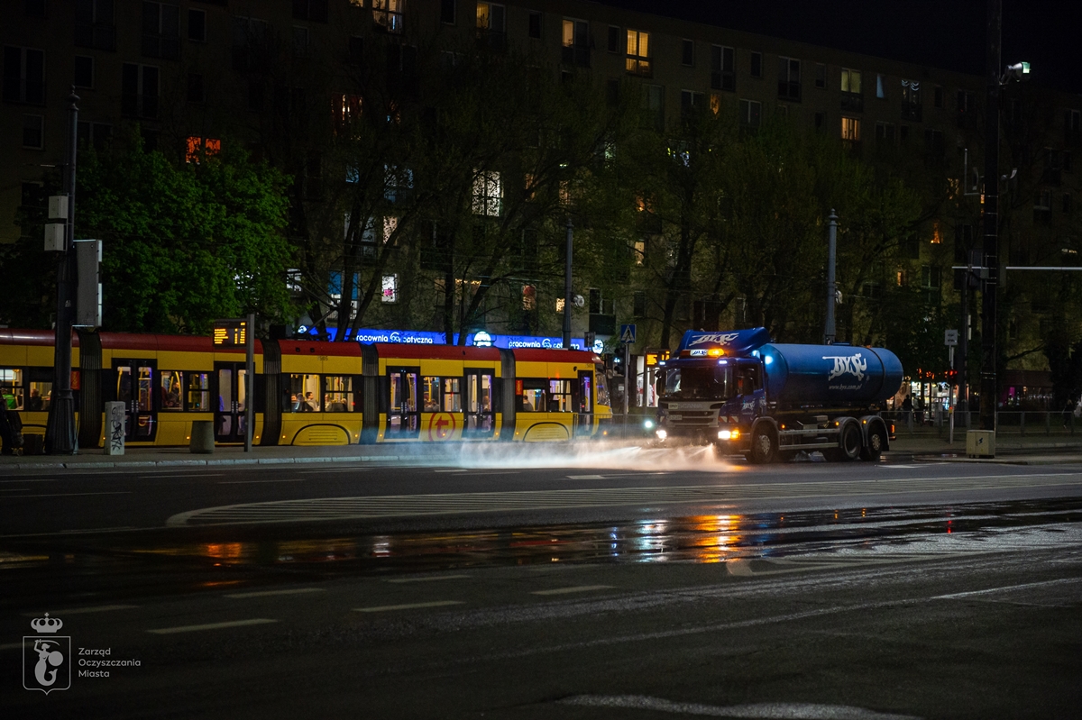 Zmywarka myje ulice nocą, w tle przejeżdża tramwaj