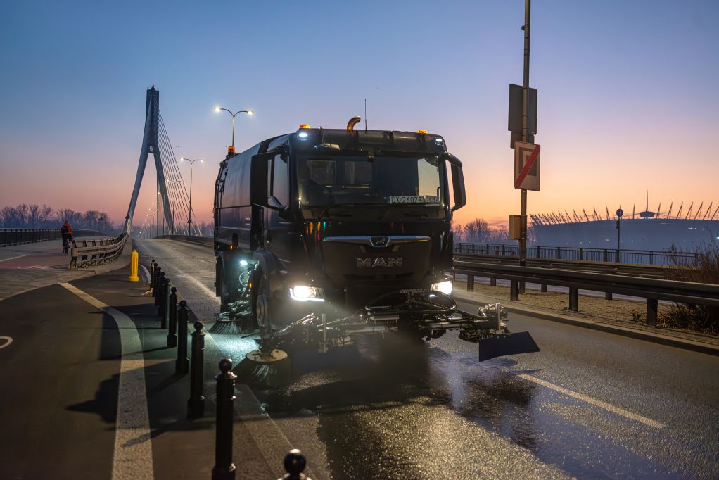 Zamaitarka uliczna czyści jezdnię mostu, jest wczesny ranek, w tle sylwetka stadionu