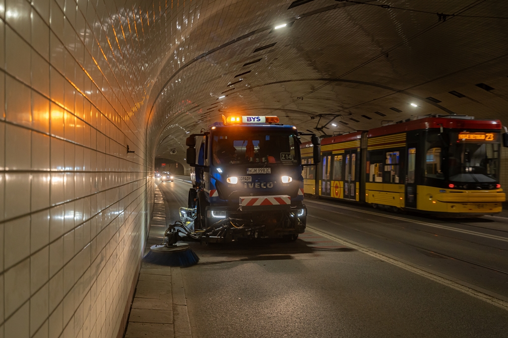 Zamiatarka sprząta ulicę w tunelu, w tle tramwaj