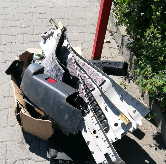 Śmieci oparte o przystanek autobusowy. Z kartonu wystają plastikowe elementy.
