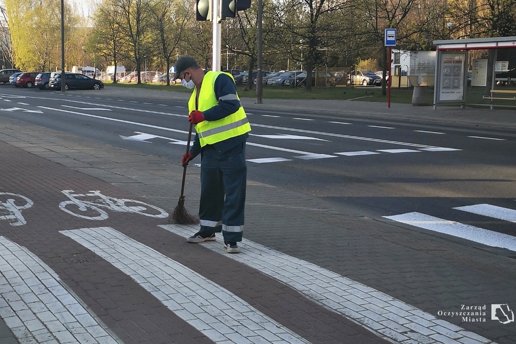 Pracownik służby oczyszczania zamiata trasę dla rowerów