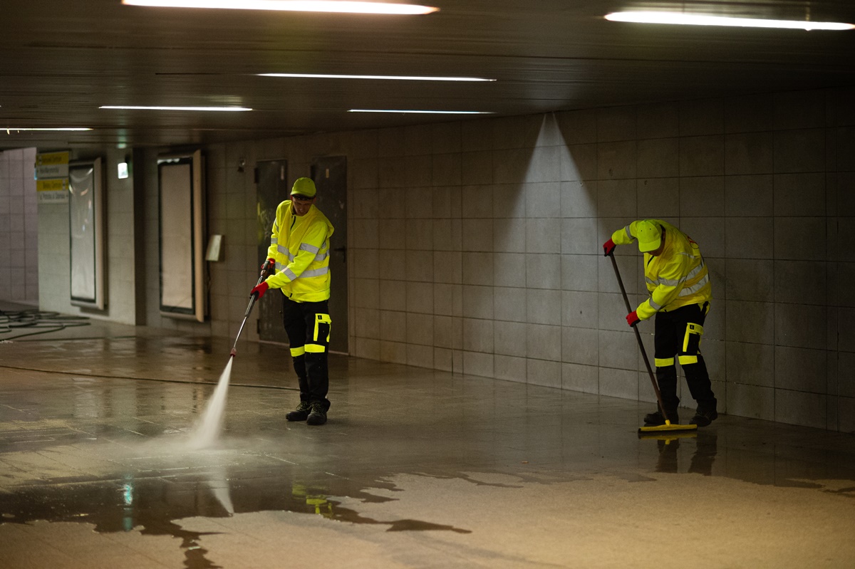 Dwóch mężczyzn myjkami ciśnieniowymi czyści chodnik przejścia podziemnego