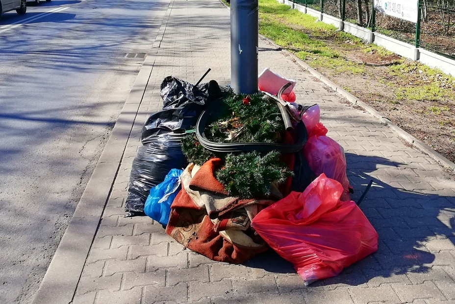 Porzucone śmieci w workach leżą na chodniku, z jednego z nich wystaje sztuczna choinka, widać też dywan, w tle ulica.