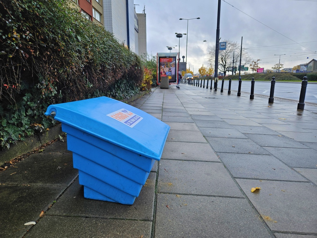 Skrzynia ustawiona na chodniku, w tle przystanek autobusowy